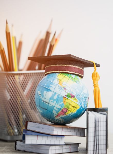 Globo terráqueo con birrete de graduación sobre libros